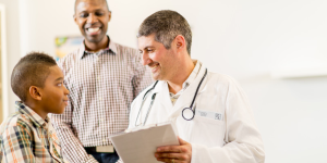 Doctor talks with a young male patient and presumably his father in this stock photo
