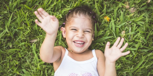 Happy toddler lying in the grass and smiling - stock photo